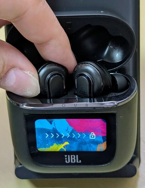 イヤーピースが外向きに収納されたJBL TOUR PRO 2を指で摘まもうとしている様子