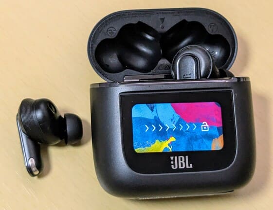 テーブルに置かれたJBL TOUR PRO 2の画像。左のイヤホン本体はケースからとり出されている。