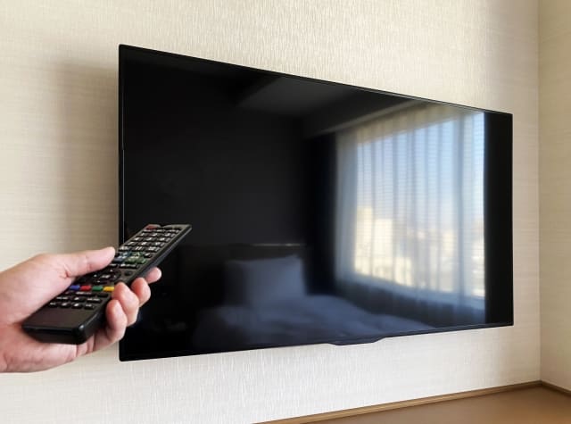 65インチテレビに向かってリモコンを向けている画像