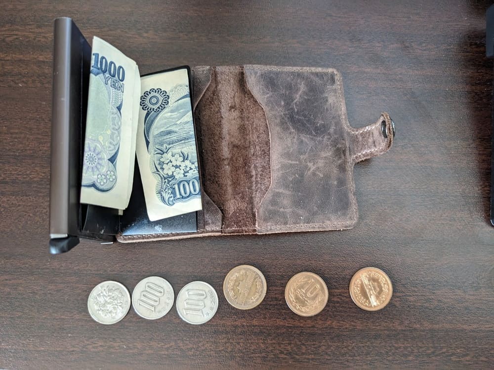 1000円札が収納してあるSecridのミニウォレットと小銭が並んでいる画像
