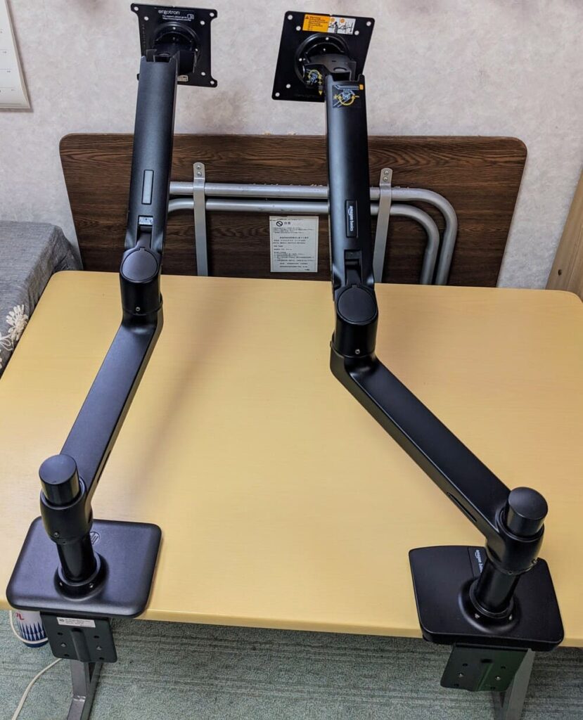 2つのエルゴトロンLXのOEM商品をテーブルに取り付けている画像