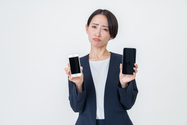 困り顔で携帯を持つ女性の画像