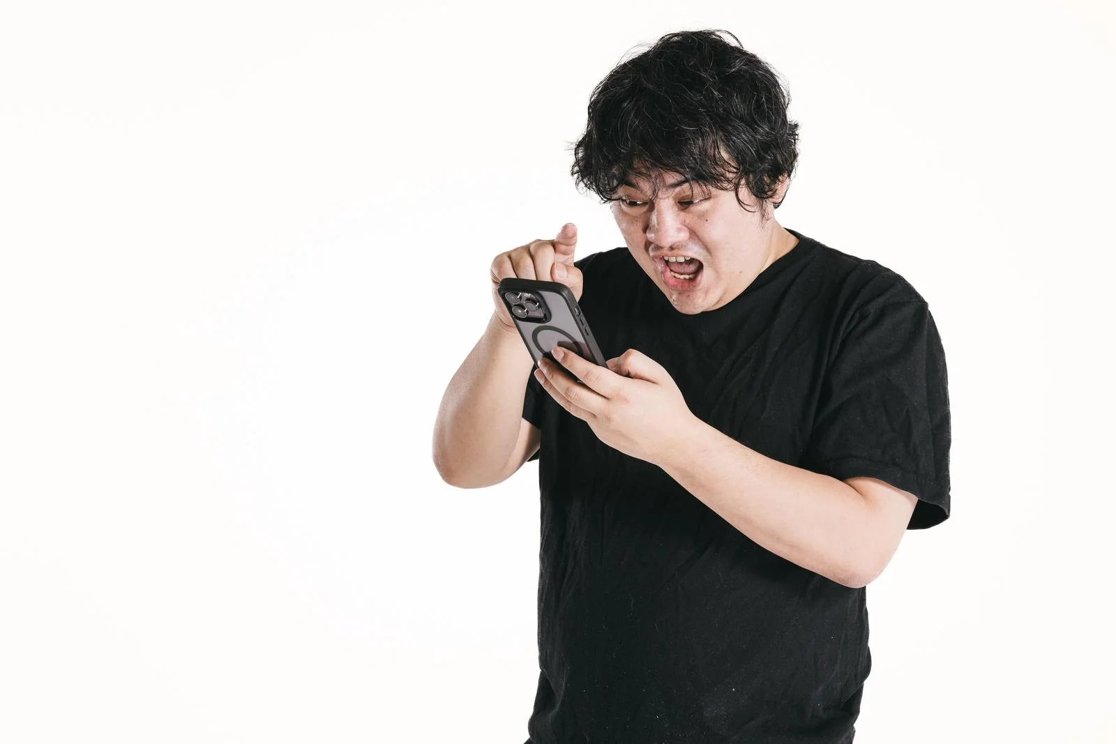 怒り顔でスマホを操作する男性の画像