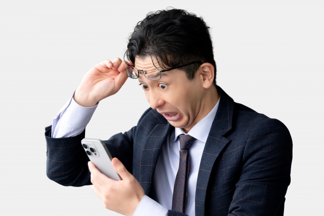 スマホを見て驚く男性ビジネスマンの画像