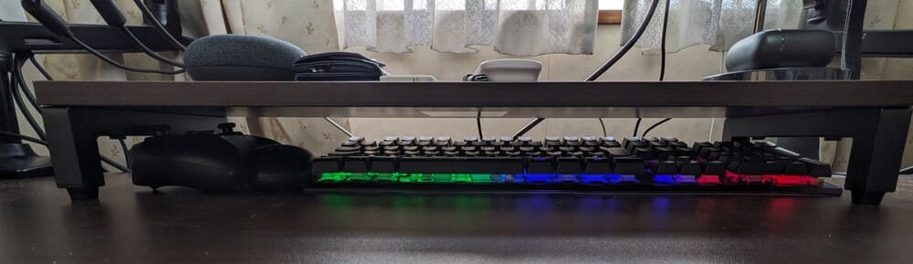 デスクシェルフの下にデバイスを収納してある画像