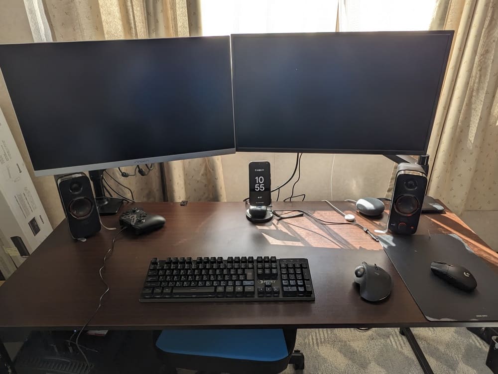 デュアルモニターと複数のデバイスがあるパソコンデスクの画像