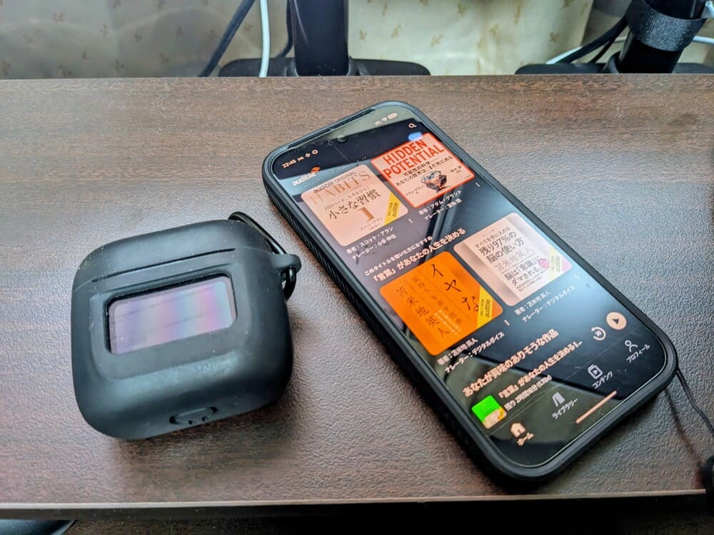 Audibleのアプリを開いたスマホとワイヤレスイヤホンの画像